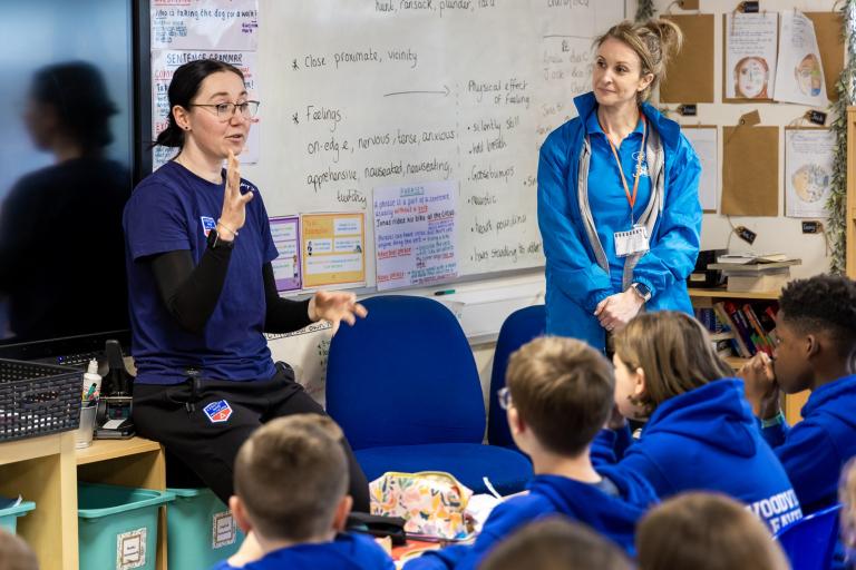 Two women standing at the front of a classroom of children.